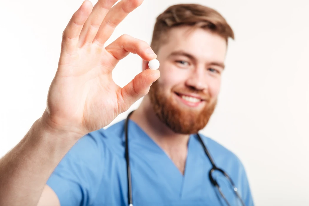 Portrait of a young male medical doctor offering a pill