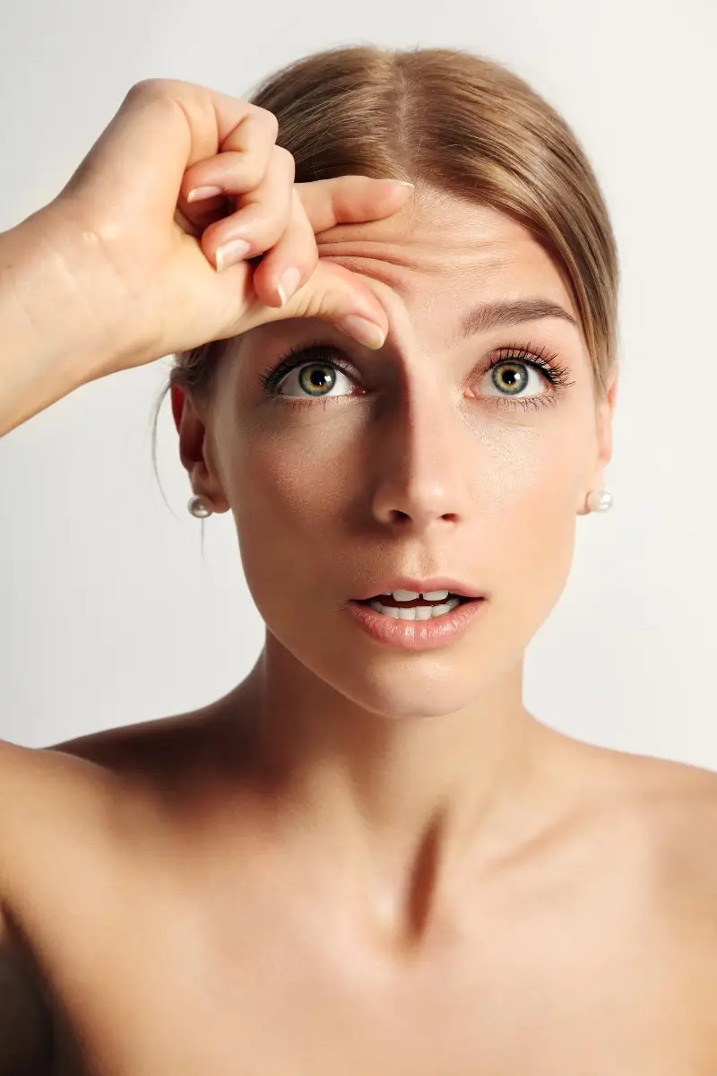 Young beauty woman wondering that she have wrinkles on her forehead