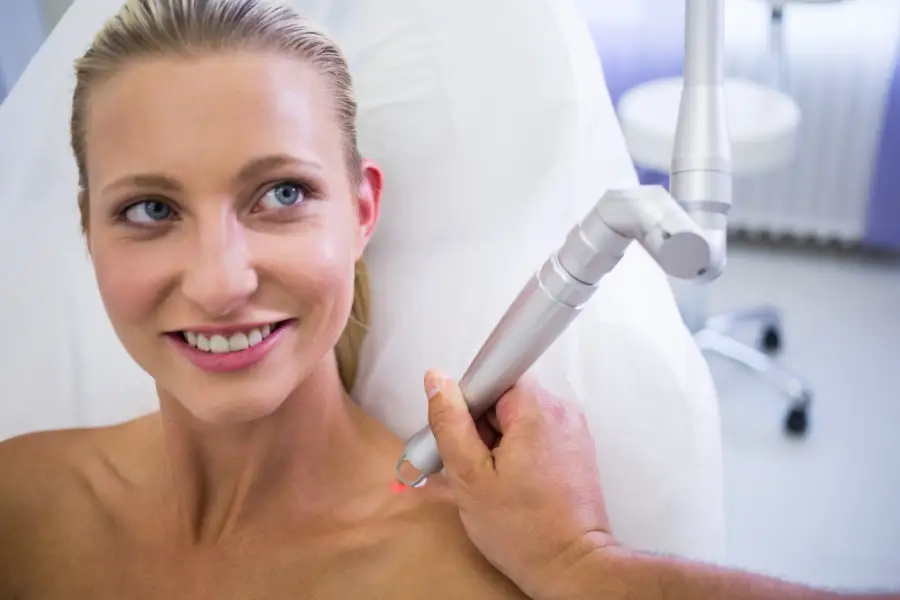 Dermatologist removing mole from womans shoulder